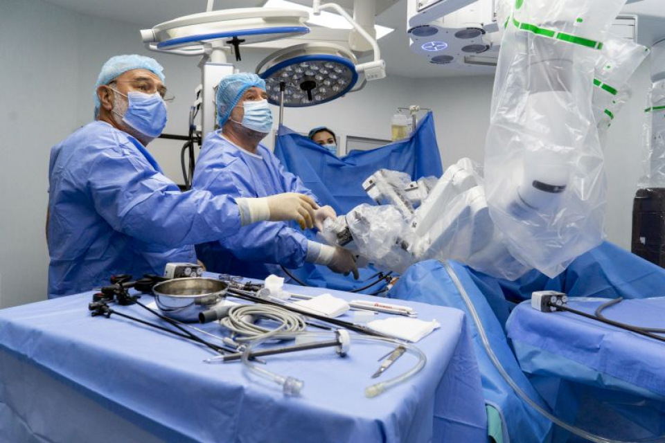 Poziționarea brațelor operatorii ale robotului chirurgical. Dr. Bogdan Marțian (stânga) și Dr. Eugen Mihăilă. Foto: SANADOR
